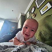 Theo joined the competition — help win amazing prizes! baby, smiling, infant, blanket, white_clothing, face, indoor, wall_art, decor, green_wall, couch, happy, portrait, head, child, cozy, home, person, toddler, curtains