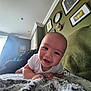 baby, smiling, infant, blanket, white_clothing, face, indoor, wall_art, decor, green_wall, couch, happy, portrait, head, child, cozy, home, person, toddler, curtains