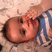 Adam participe au concours pour gagner de l'argent avec cette photo : baby, infant, child, face, hand, blue_striped_shirt, lying_down, blanket, pattern, curious, wide_eyes, skin, mouth, nose, hair, cute, indoors, playful, expression, young