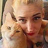 affection, animal, blonde_hair, casual_clothing, cat, chair, closeup, comfort, cute, feline, home, indoor, light, pet, piercing, portrait, red_lipstick, selfie, tattoo, woman