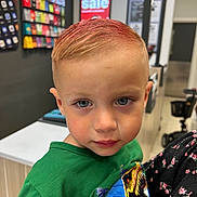 Lucas is registered to the contest to win money with this photo: blue_eyes, boy, casual, child, closeup, clothing, counter, curious, dinosaur, display, face, green_shirt, hair, holding, indoor, person, portrait, short_hair, sign, store