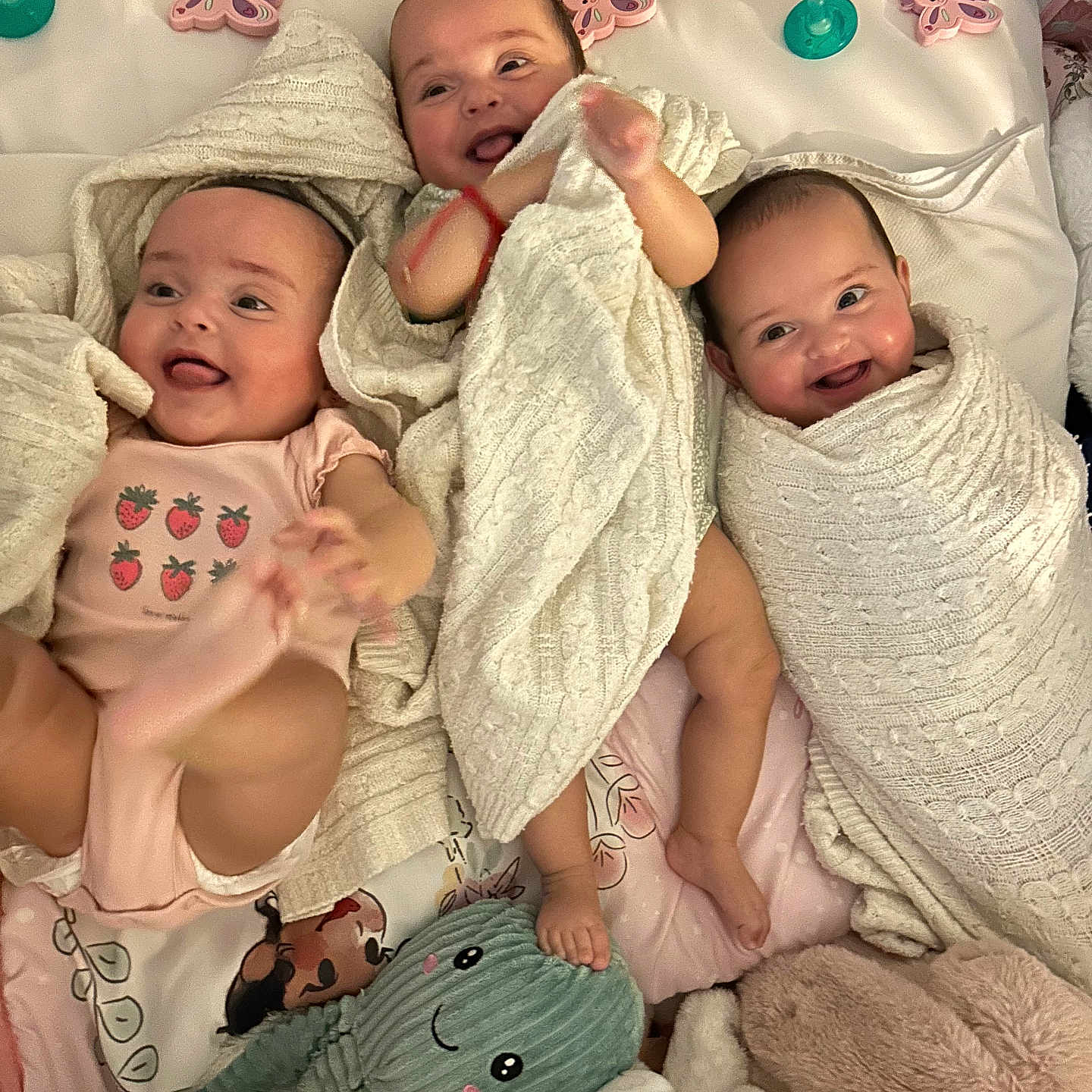 Jaretzzy is registered to the contest to win money with this photo: baby, blanket, child, crib, cushion, cute, floral_pattern, foot, happy, head, indoor, infant, knitted_blanket, lying_down, pink_onesie, playful, smiling, soft_toy, swaddled, toddler