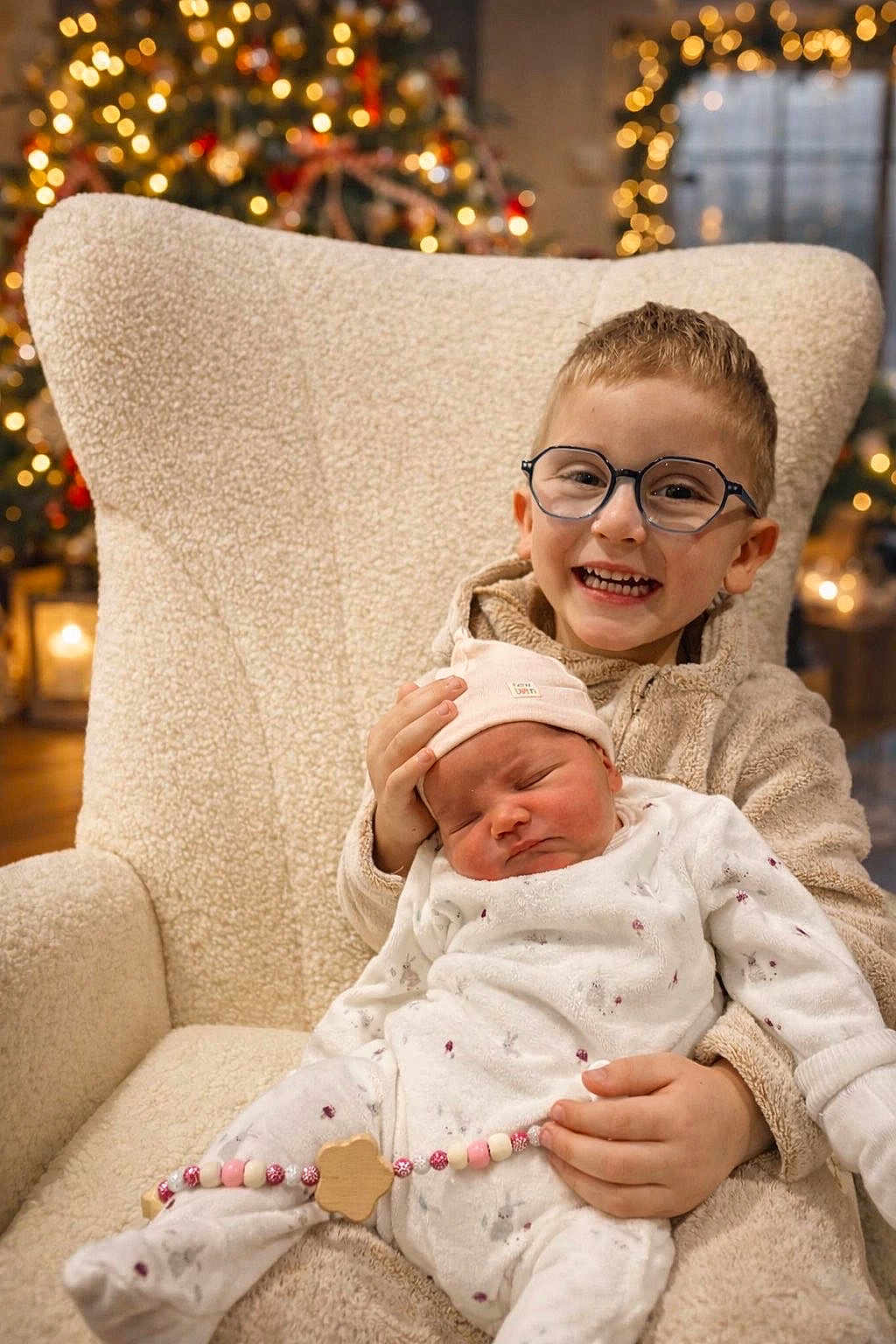 Rachel a rejoint le concours — aidez-le/la à gagner de superbes lots ! child, baby, glasses, smiling, sleeping, chair, holiday_lights, christmas_tree, cozy_clothing, indoor, family, cute, infant, toddler, warm_lighting, festive, decorations, happy, portrait, seated