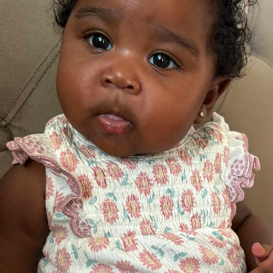 Zuraya is registered to the contest to win money with this photo: baby, child, girl, curly_hair, headband, floral_pattern, pink_pants, sitting, couch, indoor, portrait, cute, expression, earrings, casual_clothing, infant, skin, person, young_child, adorable