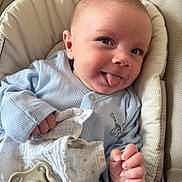 Bobby is registered to the contest to win money with this photo: baby, infant, blue_onesie, blanket, pacifier, smiling, tongue_out, cushioned_seat, cute, hand, face, portrait, child, comfort, indoor, soft_toys, happy, closeup, newborn, playful
