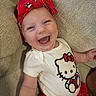 baby, child, smiling, laughing, headband, red_headband, hello_kitty, white_shirt, red_shorts, couch, beige_couch, happy, cute, infant, person, indoor, portrait, clothing, fabric, head