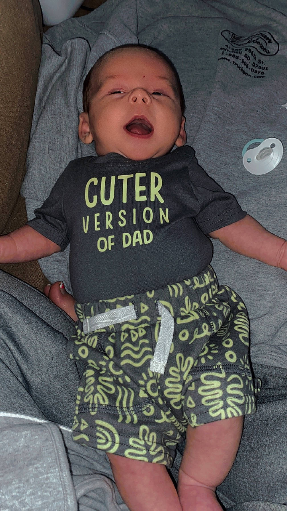 Joey is registered to the contest to win money with this photo: baby, baby_products, baby_toddler_clothing, child, comfort, cool, eye, facial_expression, finger, fun, hairstyle, happy, human_leg, pattern, person, skin, sleeve, t_shirt, textile, thigh