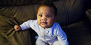 Raven is registered to the contest to win money with this photo: baby, child, infant, onesie, couch, sofa, brown, torn, curious, face, sitting, indoors, furniture, young, cute, expression, home, soft, cloth, seat