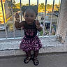 bracelets, child, concrete, daytime, fashion, footwear, girl, happy, outdoor, pigtails, railing, residential_area, sandals, skirt, smiling, standing, sunlight, toddler, top, urban