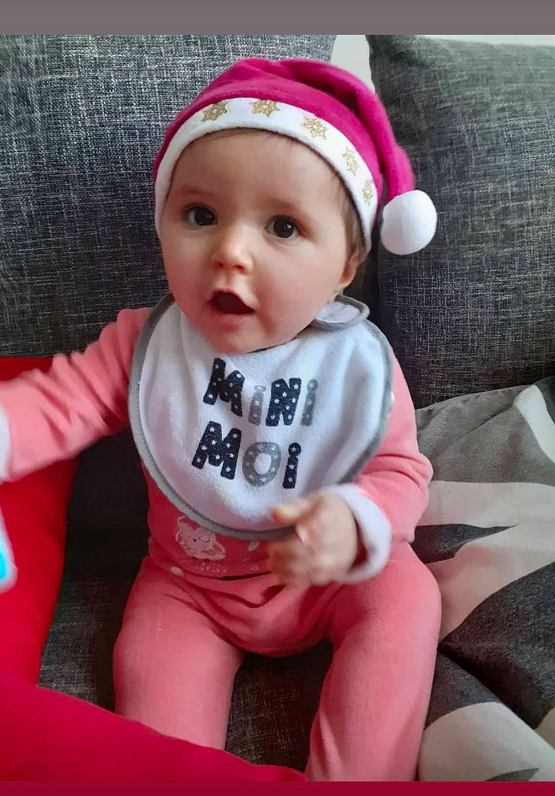 Louhna participe au concours pour gagner de l'argent avec cette photo : baby, baby_products, baby_toddler_clothing, bonnet, cheek, child, comfort, costume_accessory, couch, headwear, person, pink, skin, sock, surprise, toddler