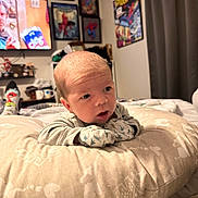 Dru is registered to the contest to win money with this photo: baby, infant, pillow, mittens, bedroom, poster, spiderman, tv, television, socks, curious, resting, soft, cozy, indoor, person, child, cute, expression, furniture