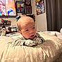 baby, infant, pillow, mittens, bedroom, poster, spiderman, tv, television, socks, curious, resting, soft, cozy, indoor, person, child, cute, expression, furniture