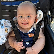 Jhosua is registered to the contest to win money with this photo: baby, infant, stroller, harness, blanket, smile, blue_eyes, chubby_cheeks, onesie, star_pattern, bear_print, hands, fingers, seat, straps, portrait, closeup, candid, sunlight, cute