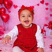 Anela joined the competition — help win amazing prizes! baby, infant, smiling, red_headband, red_dress, hearts, balloons, valentine_theme, pink_background, sitting, portrait, happy, cute, gift_boxes, wrapped_gifts, heart_garland, blanket, white_tights, studio_photo, chubby_cheeks