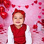 baby, toddler, smile, red_dress, headband, bow, valentines, heart_balloons, pink_background, garland, gift_boxes, sitting, portrait, studio, happy, rosy_cheeks, blanket, hands, cute, festive