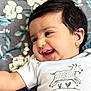 Aaira is registered to the contest to win money with this photo: baby, child, infant, smiling, happy, face, hair, onesie, clothing, goat_illustration, patterned_blanket, floral, lying_down, cute, portrait, closeup, skin, cheeks, arm, baby_girl