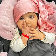 Aaira is registered to the contest to win money with this photo: baby, infant, child, face, hand, fingers, headscarf, pink, blanket, clothing, bracelet, cute, indoors, portrait, cozy, soft, sleeping_bag, sitting, closeup, person