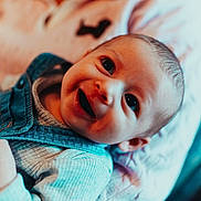 Arthur participe au concours pour gagner de l'argent avec cette photo : baby, blanket, blue, child, closeup, clothing, cozy, cute, expression, face, happy, indoors, infant, lying_down, person, portrait, smile, soft, warm, young