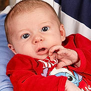 Arthur participe au concours pour gagner de l'argent avec cette photo : baby, infant, child, red_clothing, blue_eyes, hand, face, person, portrait, cute, cozy, sitting, holding, closeup, young, skin, head, expression, casual, warm