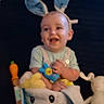 Jameson is registered to the contest to win money with this photo: baby, bunny_ears, toy, basket, smiling, child, indoor, plush_toy, blue_clothing, cute, face, happy, soft_toy, person, headwear, carrot_toy, animal_theme, playful, infant, seated