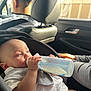 Eithan joined the competition — help win amazing prizes! baby, bottle, car_seat, infant, milk, child, car_interior, person, seatbelt, headrest, window, sunlight, clothing, hand, adult, travel, road_trip, relaxing, portrait, casual