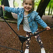 Emma participe au concours pour gagner de l'argent avec cette photo : child, girl, smiling, denim_jacket, leggings, white_shoes, rope, playground, outdoor, forest, tree, nature, happy, casual_clothing, young, fun, active, daylight, portrait, cute