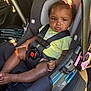 baby, black_hair, bow, car_door, car_interior, car_seat, car_seat_base, car_seat_buckle, car_seat_strap, child, clothing, infant, pink, safety, seat_belt, serious_expression, sitting, sunlight, toddler, vehicle