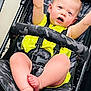 baby, child, stroller, yellow_clothing, camo_pattern, barefoot, happy, raising_arms, indoor, seatbelt, infant, person, cute, expression, legs, feet, black_frame, fabric, playful, face