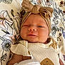 Oakleigh is registered to the contest to win money with this photo: baby, bow, child, close_up, clothing, cute, fabric, face, floral_blanket, headband, indoors, infant, lying_down, newborn, pattern, portrait, smiling, soft_lighting, white_mitten, winking