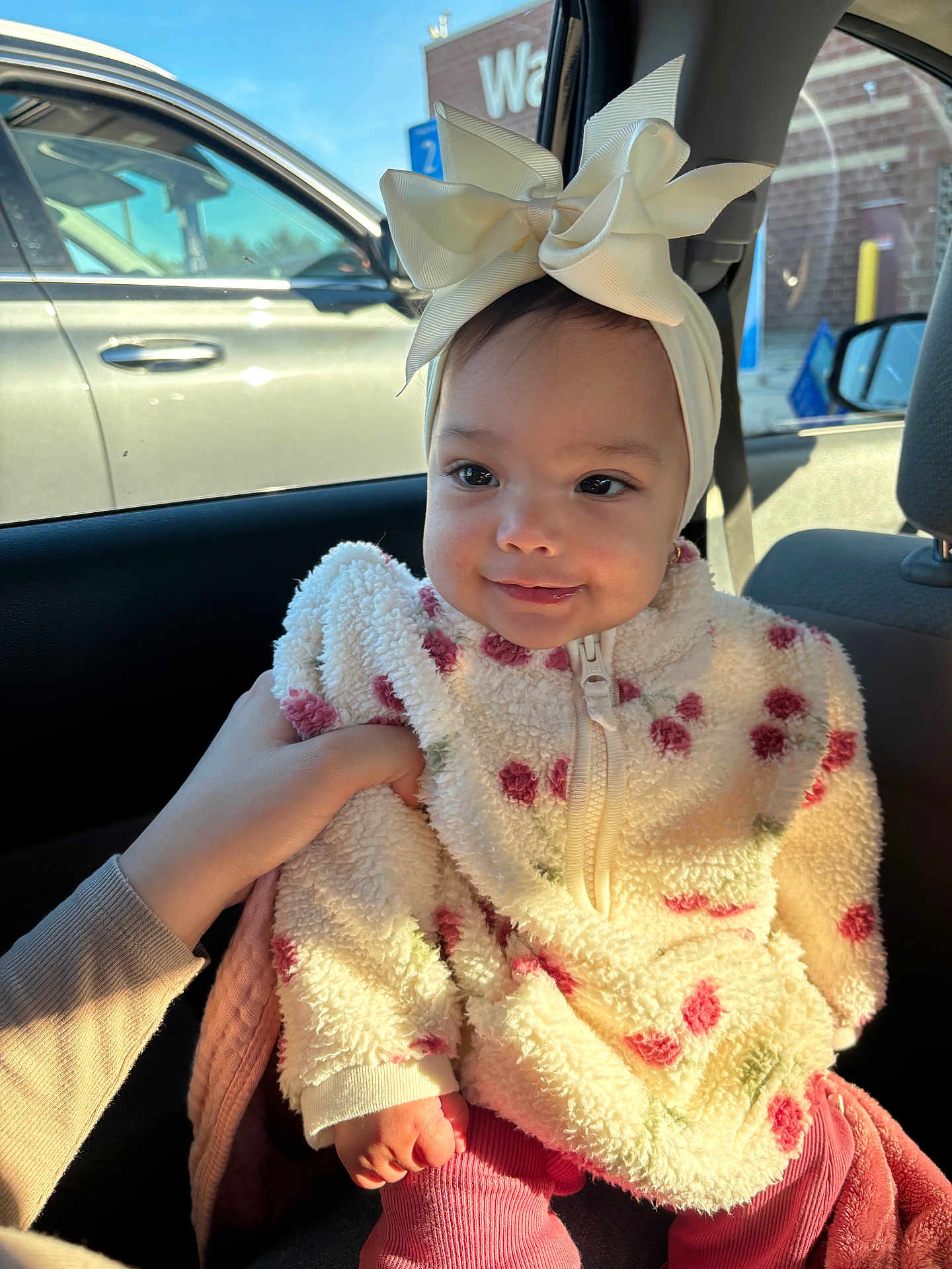 Arleth joined the competition — help win amazing prizes! baby, child, infant, headband, bow, jacket, floral_pattern, car_interior, seat, sunlight, hand, smile, face, cute, pink_pants, window, car, person, portrait, clothing