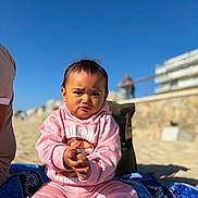 Isalei a rejoint le concours — aidez-le/la à gagner de superbes lots ! child, toddler, pink_clothing, beach, sand, blue_sky, sunny, towel, outdoor, portrait, casual, young_child, person, sitting, daylight, serious_expression, clothing, vacation, holiday, playful