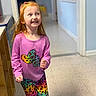 Brooklynn is registered to the contest to win money with this photo: child, girl, red_hair, pink_shirt, colorful_clothing, rainbow_leggings, indoor, hallway, smiling, happy, motion, floor, wall, doorway, person, long_hair, cute, playful, bright, casual_wear