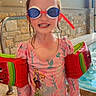 child, swimming_pool, goggles, floaties, pink_swimsuit, princess_characters, indoor_pool, tiled_floor, stone_wall, water, smiling, wet_hair, playful, sparkles, safety, fun, summer, water_fun, young_child, happy