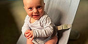 Nathan is registered to the contest to win money with this photo: baby, infant, child, smiling, sitting, baby_rocker, clothing, onesie, indoors, carpet, toy, colorful, face, happy, cute, hands, foot, head, person, portrait