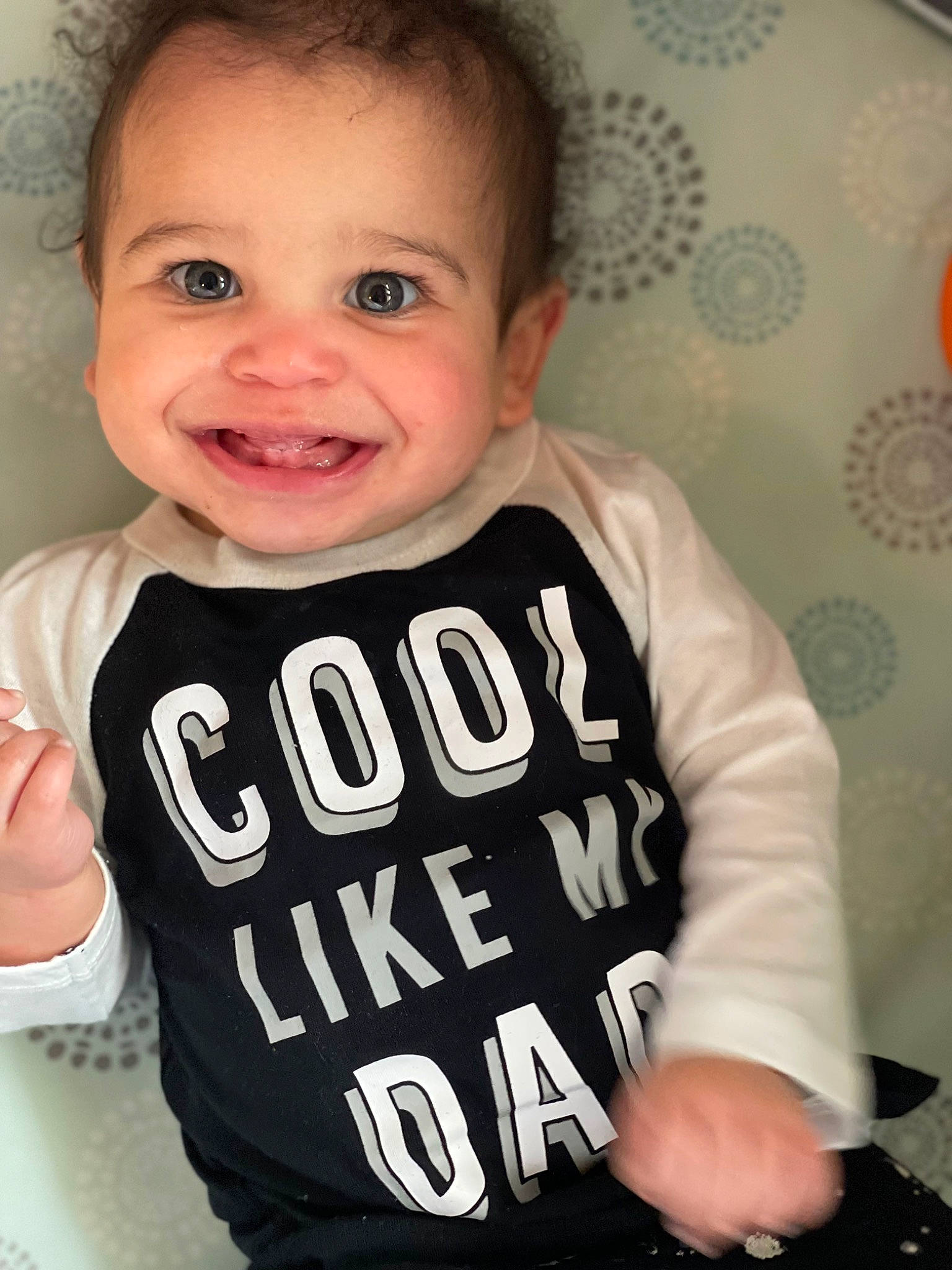 Kj is registered to the contest to win money with this photo: baby, baby_toddler_clothing, cheek, child, chin, eyelash, face, facial_expression, font, gesture, happy, jersey, joy, long_sleeved_t_shirt, neck, person, skin, sleeve, smile, sportswear