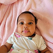 Ava joined the competition — help win amazing prizes! baby, infant, child, pink_blanket, flamingo_print, white_shirt, tongue_out, cute, lying_down, soft_texture, indoors, portrait, happy, curious, face, person, skin, head, eyes, smile