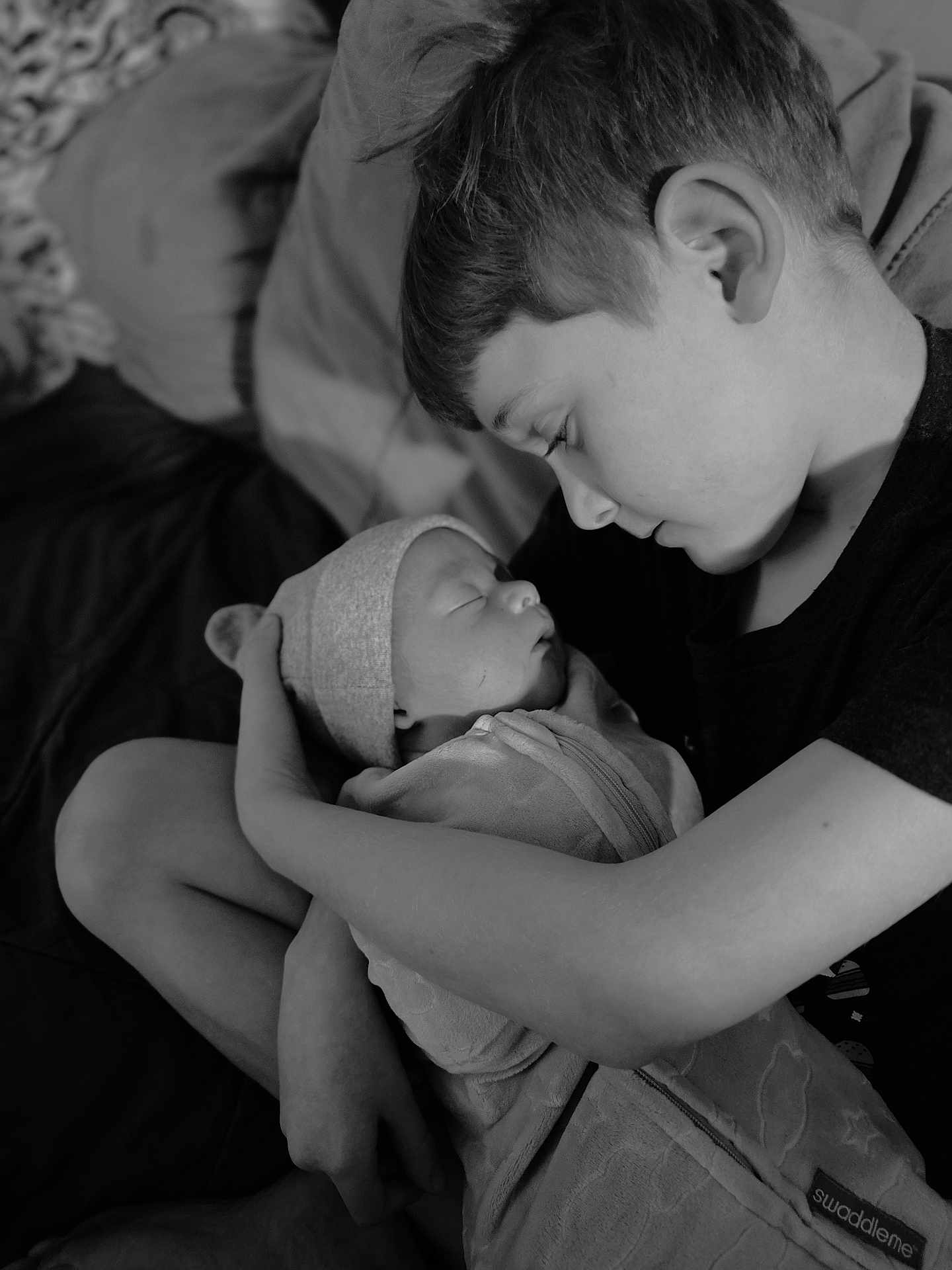 Aidan is registered to the contest to win money with this photo: child, newborn, baby, holding, swaddled, blanket, sleeping, tender, black_and_white, portrait, family, love, indoor, cozy, sibling, gentle, closeup, peaceful, person, headwear