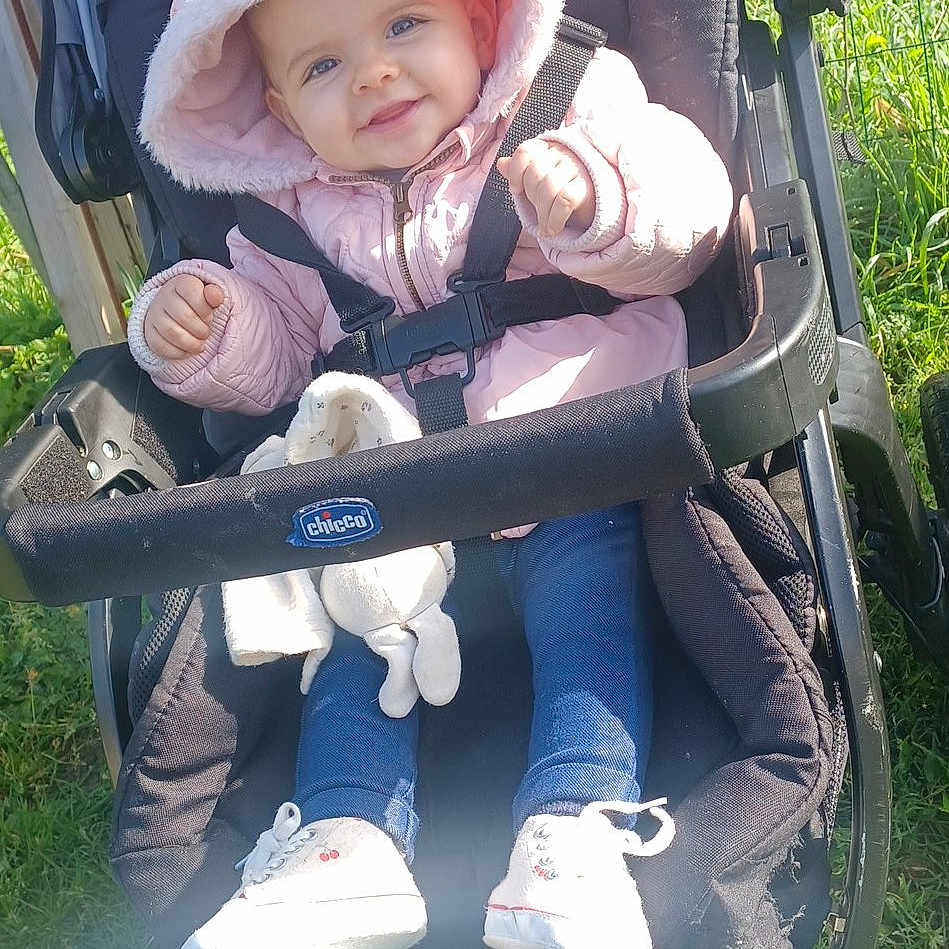 Sofia participe au concours pour gagner de l'argent avec cette photo : baby, canopy, cute, grass, harness, hooded_jacket, infant, outdoors, pink_jacket, portrait, pram, seatbelt, shoe, smiling, sneaker, stroller, stuffed_animal, sunlight, toy, wheel