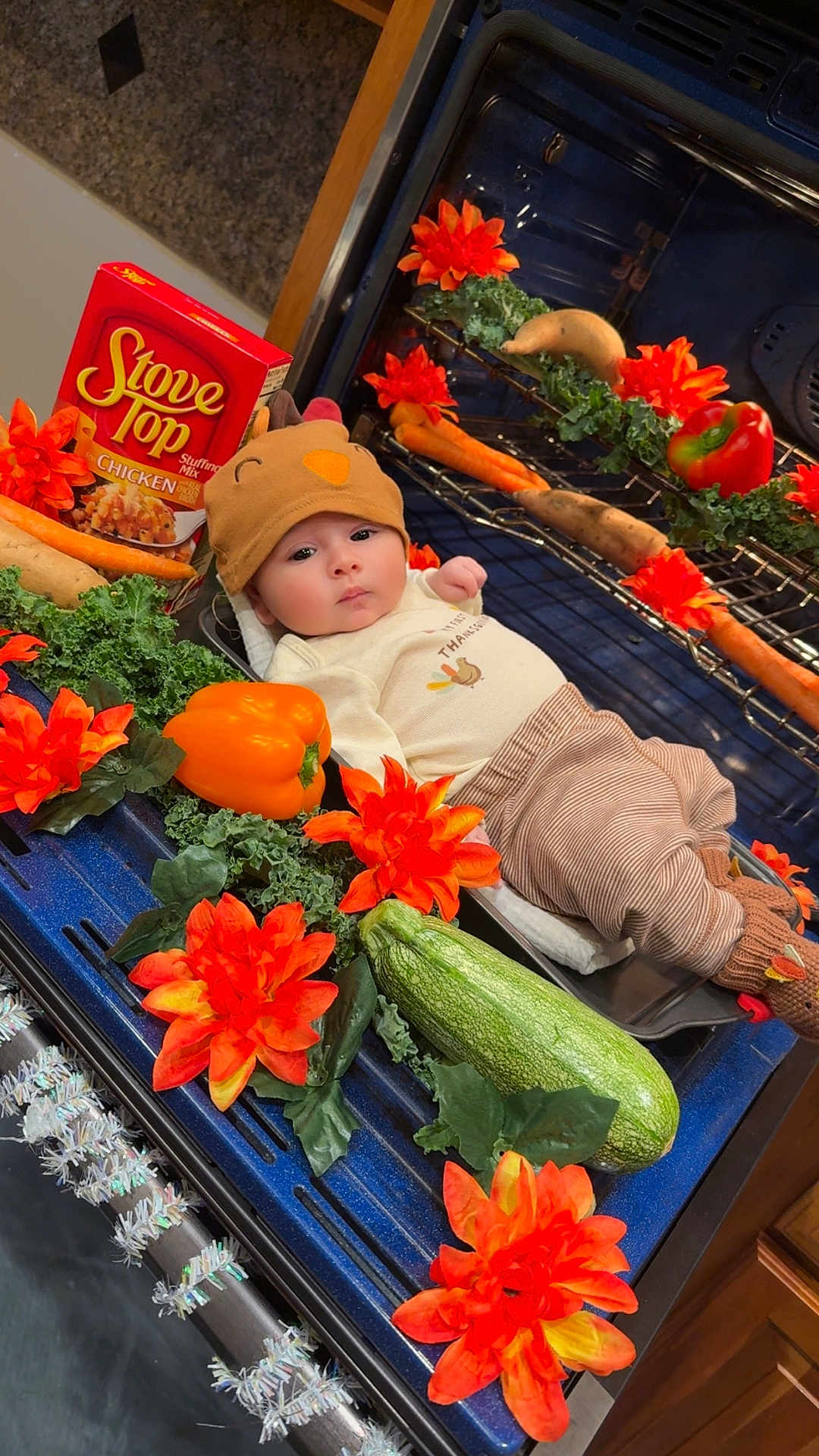 Cruz is registered to the contest to win money with this photo: baby, oven, thanksgiving, turkey_hat, flowers, orange_flowers, vegetables, zucchini, bell_pepper, carrots, stuffing_mix, kitchen, holiday, costume, cute, infant, holiday_decor, festive, cabbage, potatoes