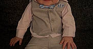 Cruz is registered to the contest to win money with this photo: baby, child, suit, bow_tie, smile, couch, indoor, portrait, cute, fashion, infant, clothing, footwear, happy, seated, person, home, young, face, casual