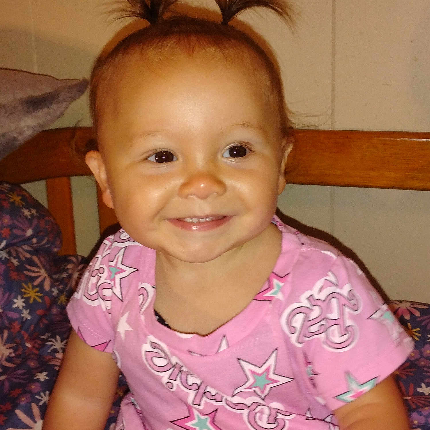 Larrea joined the competition — help win amazing prizes! blanket, child, cute, dress, face, floral, girl, happy, indoor, pattern, person, pigtails, pink, portrait, seated, smile, stars, toddler, wooden_chair, young_child