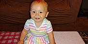 Larrea is registered to the contest to win money with this photo: baby, carpet, child, couch, cute, dress, furniture, hair_tie, happy, indoor, person, playful, room, sitting, smile, striped_clothing, table, toddler, toy, young_child