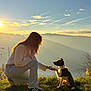 Max a rejoint le concours — aidez-le/la à gagner de superbes lots ! person, dog, puppy, grass, mountains, sunset, sunlight, sky, clouds, contrails, rock, outdoor, nature, crouching, leash, casual_clothing, interaction, pet, scenic, silhouette