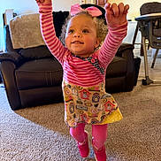 Jor Ja joined the competition — help win amazing prizes! toddler, child, jumping, pink_shoes, striped_shirt, colorful_dress, living_room, carpet, couch, high_chair, smiling, happy, arms_up, bow, curly_hair, indoor, furniture, portrait, person, playful