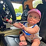 Kalani joined the competition — help win amazing prizes! baby, child, infant, cap, car_seat, steering_wheel, vehicle_interior, hand, foot, face, blue_eyes, pink_cap, romper, cute, indoors, daylight, black_leather, patriotic, expression, person