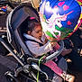 balloon, casual, chairs, child, cozy_clothing, crepes, family, heart_shaped, man, outdoor, pavement, pink_bow, playful, shoes, sign, stroller, sunlight, table, toddler, unicorn