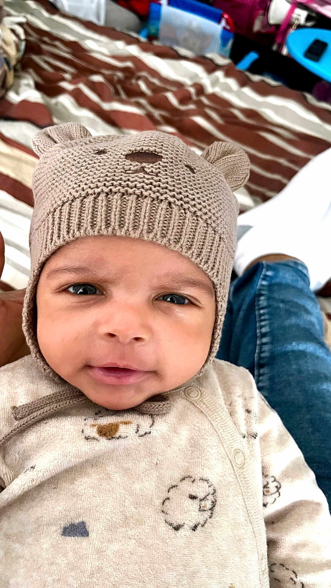 Daniel a rejoint le concours — aidez-le/la à gagner de superbes lots ! baby, infant, face, hat, knit_hat, beanie, eyes, smile, onesie, pajamas, bedding, striped_bed, blanket, close_up, portrait, cozy, denim, hand, indoor, cute