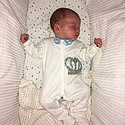 Kayden Lee joined the competition — help win amazing prizes! newborn, baby, sleeping, onesie, blue_bow_tie, crown_emblem, blanket, knitted_blanket, bassinet, crib, star_pattern, infant, peaceful, indoors, resting, cute, small_hands, soft, white, cozy