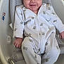 baby, onesie, teddy_bear_print, smile, baby_bathtub, mesh_support, wooden_floor, infant, child, comfortable, happy, seated, footed_pajamas, indoor, face, person, cute, small_hand, baby_clothing, infant_bath