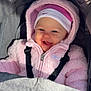 baby, child, pink_jacket, hat, smiling, stroller, seatbelt, outdoor, happy, face, blue_eyes, hood, warm_clothing, infant, cute, portrait, sunlight, cozy, babywear, winter